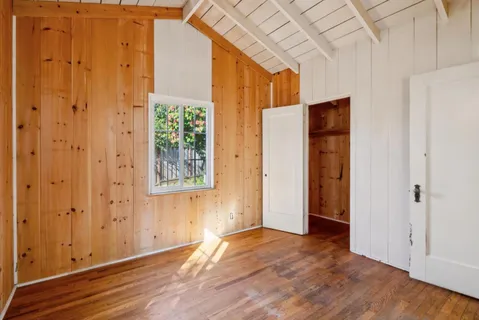a view of an empty room with wooden floor and a window