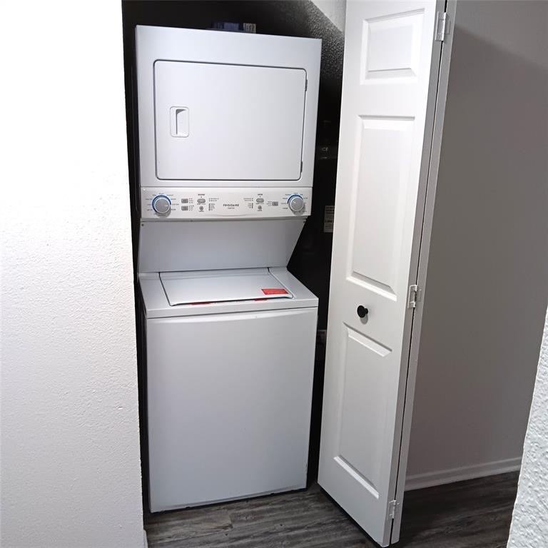 708 West Collins Street Denton, TX 76201 - Photo 11 of 40 Laundry room featuring light gray wood-pattern vinyl plank flooring, stacked washer and dryer, and a textured wall