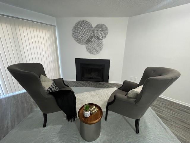 708 West Collins Street Denton, TX 76201 - Photo 14 of 40 Living area with a fireplace, a textured ceiling, and light gray wood-pattern vinyl plank flooring
