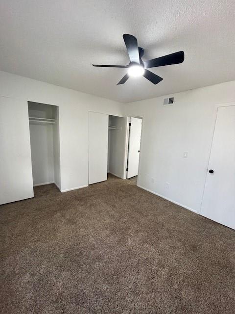 708 West Collins Street Denton, TX 76201 - Photo 29 of 40 Primary bedroom with multiple closets, wall-to-wall carpet, a ceiling fan, and a textured ceiling