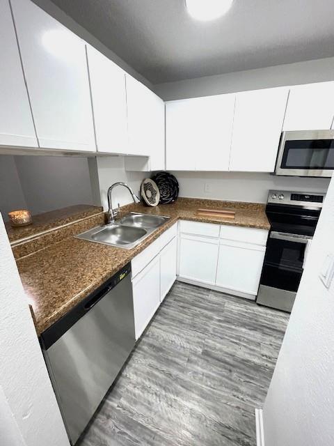 708 West Collins Street Denton, TX 76201 - Photo 6 of 40 Kitchen featuring stainless steel appliances, light gray wood-pattern vinyl plank flooring, white cabinets, and a textured ceiling