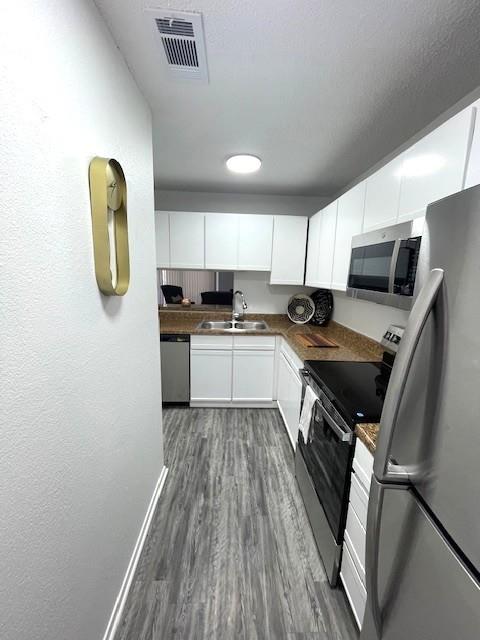 708 West Collins Street Denton, TX 76201 - Photo 8 of 40 Kitchen featuring stainless steel appliances, light gray wood-pattern vinyl plank flooring, white cabinets, and a textured ceiling