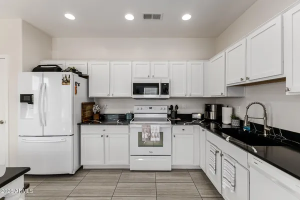 a kitchen with granite countertop white cabinets and white appliances