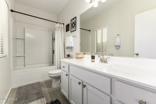 a bathroom with a double vanity sink toilet mirror and shower