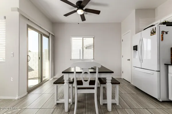 a white kitchen with a refrigerator a table and chairs