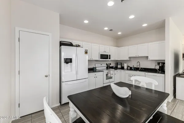 a kitchen with stainless steel appliances granite countertop a sink a stove a refrigerator and white cabinets with wooden floor
