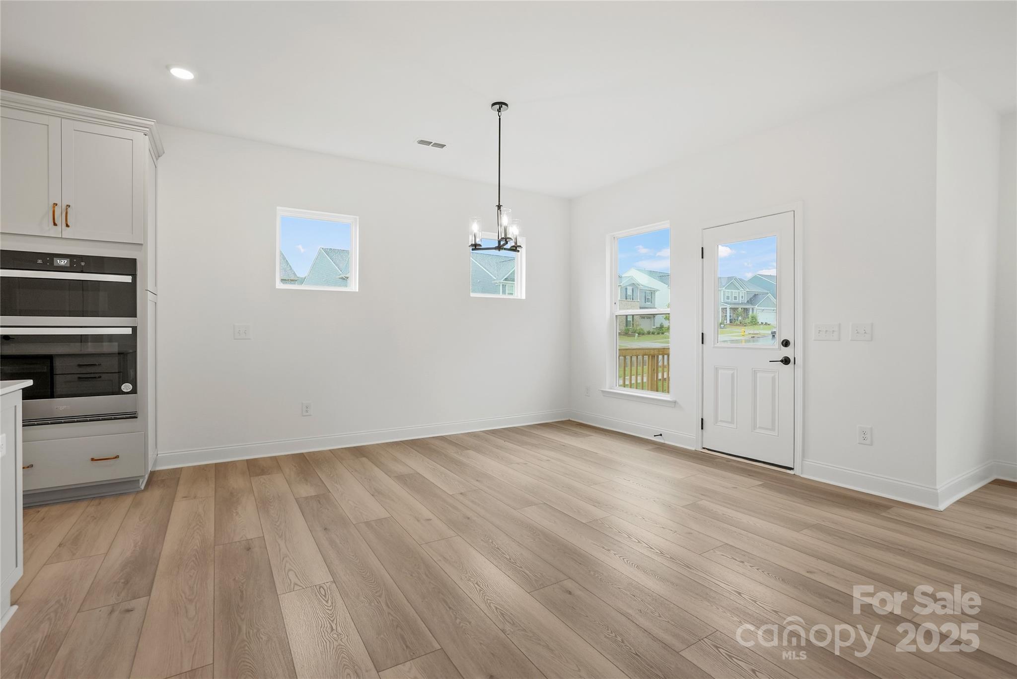 9373 Moss Plantation Avenue Northwest Concord, NC 28027 - Photo 12 of 27 an empty room with wooden floor cabinet and windows