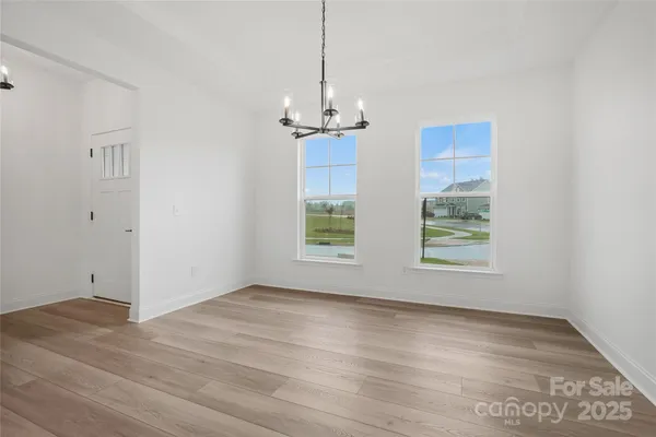 a kitchen with stainless steel appliances granite countertop a stove top oven a sink a refrigerator and white cabinets with wooden floor