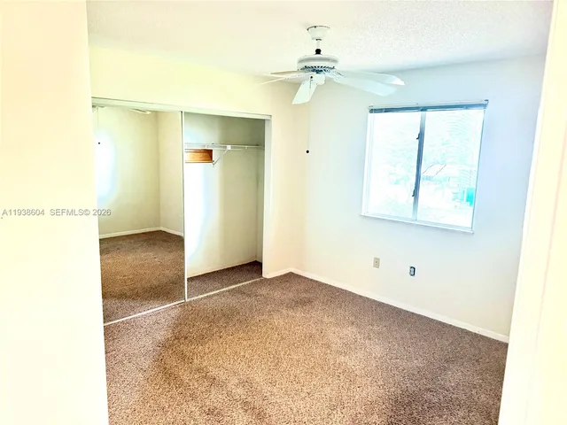an empty room with a window and a ceiling fan