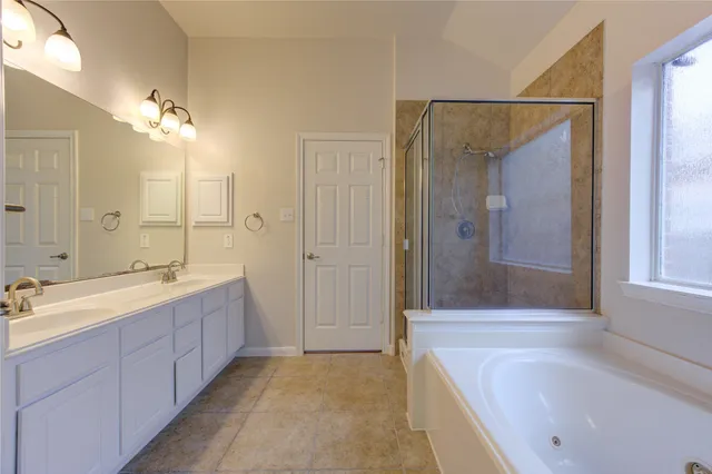a spacious bathroom with a tub sink shower and mirror