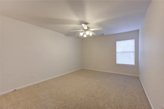 an empty room with a chandelier fan and windows
