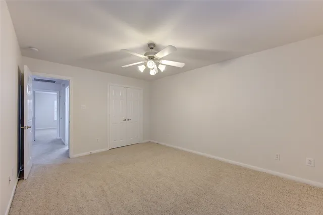 an empty room with a chandelier fan and windows