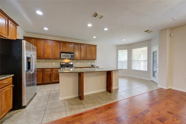 a kitchen with granite countertop a stove a sink and a refrigerator