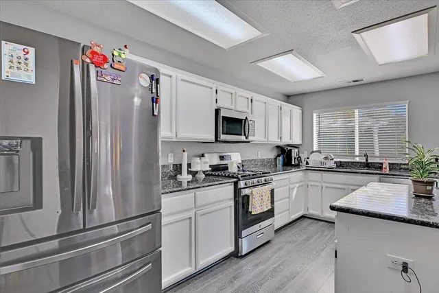 a kitchen with stainless steel appliances granite countertop a refrigerator stove microwave and sink