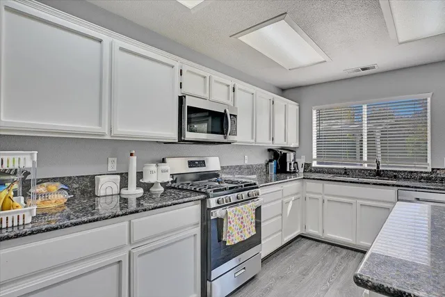 a kitchen with granite countertop a sink a stove and cabinets