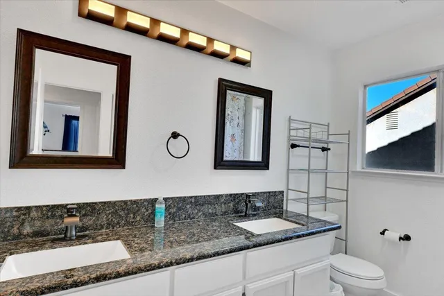 a bathroom with a granite countertop sink a toilet and shower