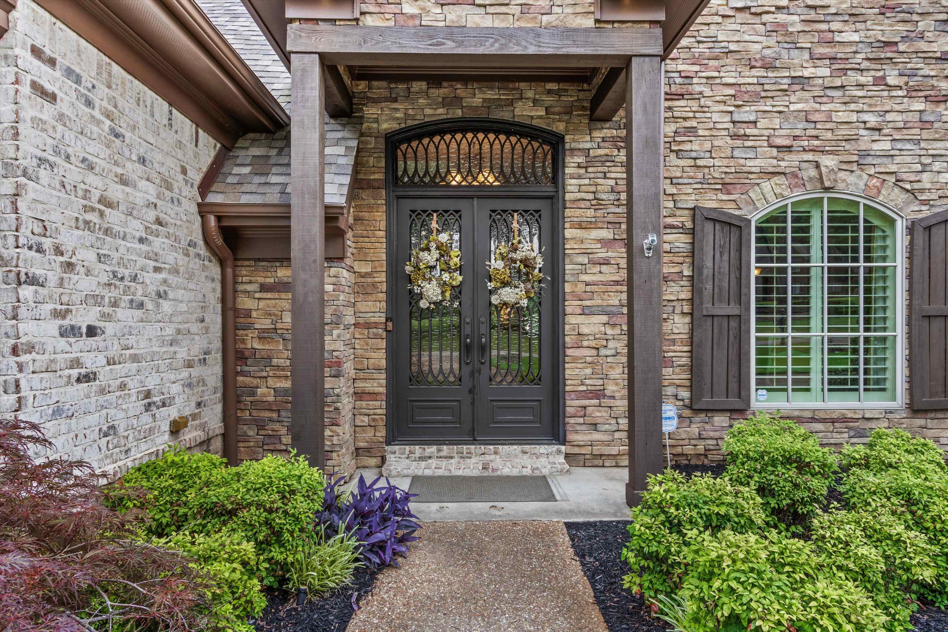 150 Ridgecrest Drive Arlington, TN 38002 - Photo 4 of 40 Stone facade entry featuring decorative double doors, an arched transom, and a complementary arched window with shutters