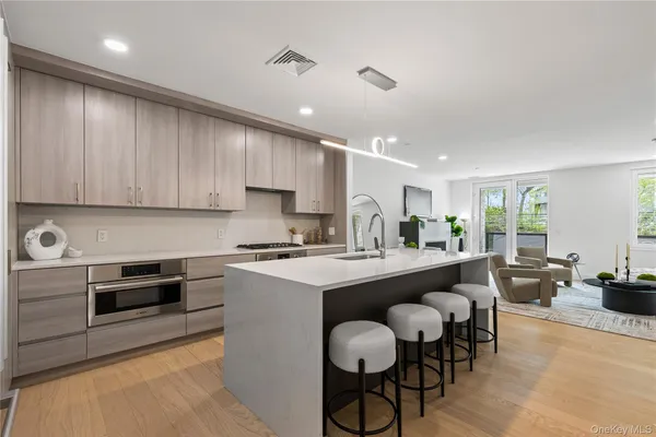 a kitchen with stainless steel appliances granite countertop a stove top oven a sink dishwasher and white cabinets with wooden floor