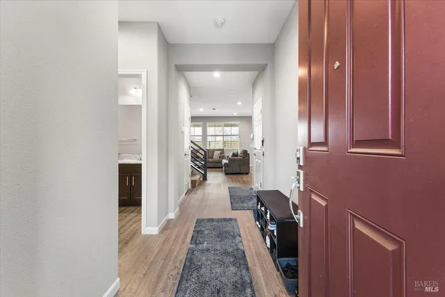 a hallway with a view of living room with wooden floor