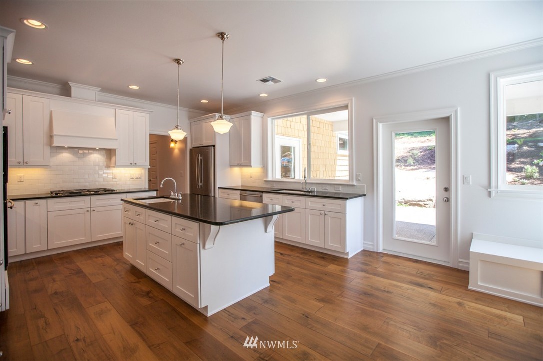 474 Whitecap Road Bellingham, WA 98229 - Photo 8 of 13 a kitchen with stainless steel appliances kitchen island granite countertop a stove a sink a refrigerator and white cabinets with wooden floor