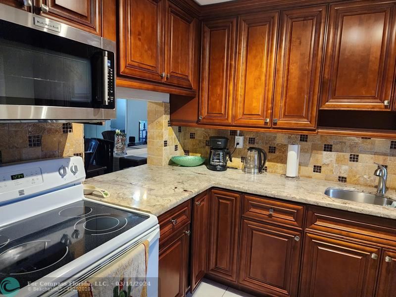 a kitchen with granite countertop stainless steel appliances a stove a sink and a microwave