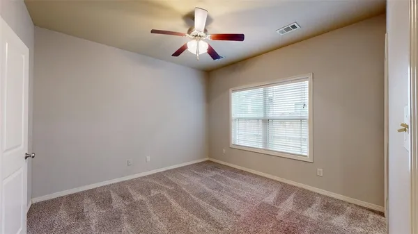 an empty room with a window and a ceiling fan
