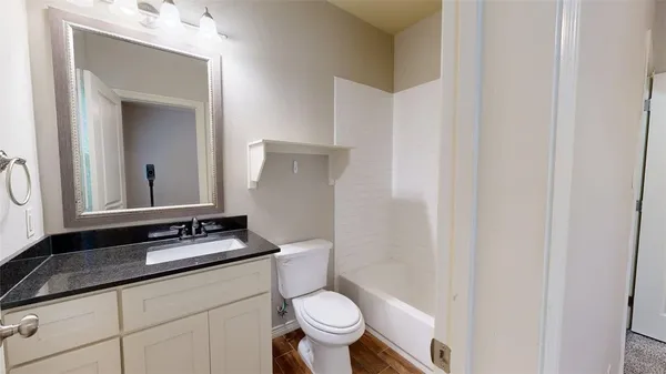 a bathroom with a granite countertop sink a toilet and a mirror