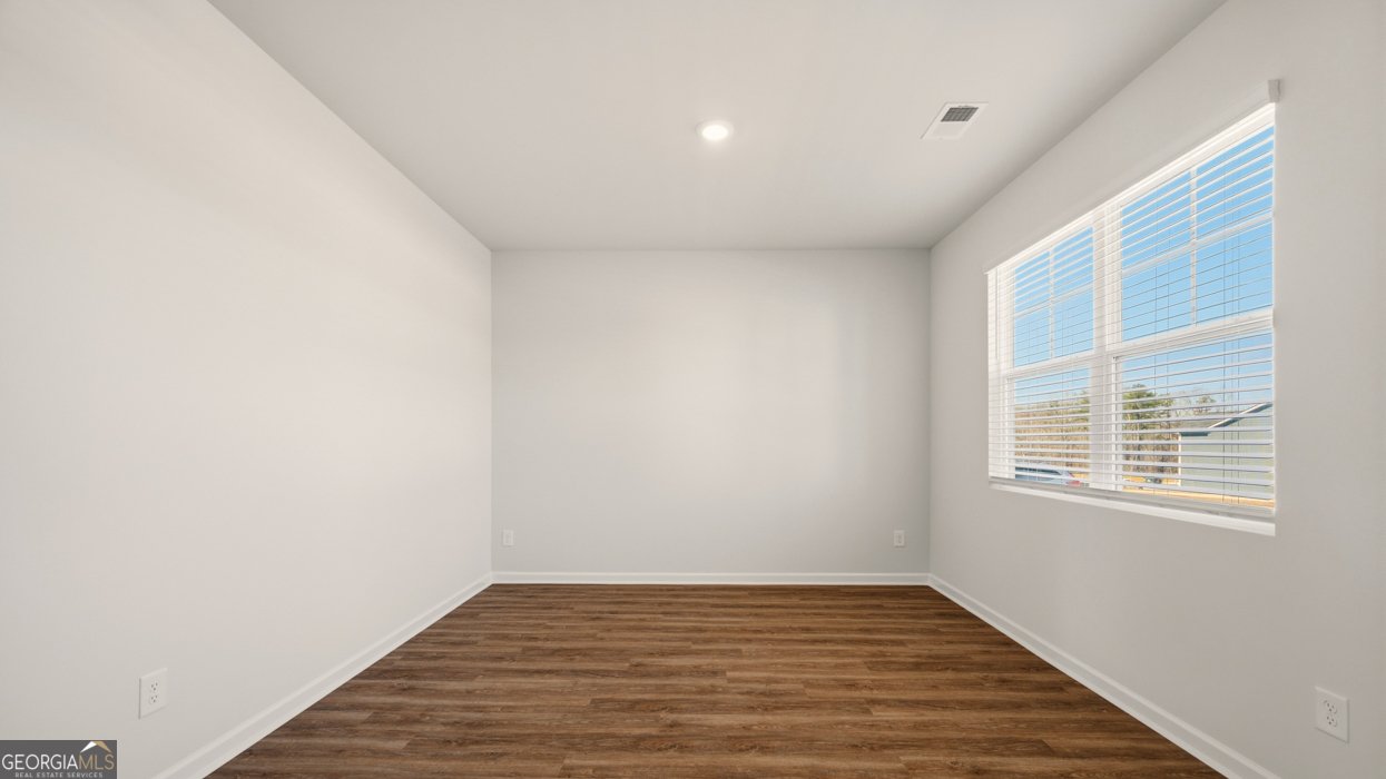 8578 Seabiscuit Road Lithonia, GA 30058 - Photo 4 of 30 a view of an empty room with wooden floor and a window