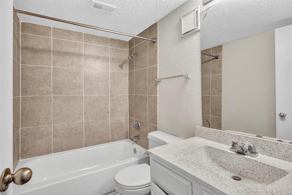 11311 Audelia Road, Unit 271 Dallas, TX 75243 - Photo 13 of 17 Full bathroom featuring a textured ceiling, tiled shower / bath combo, vanity, and toilet