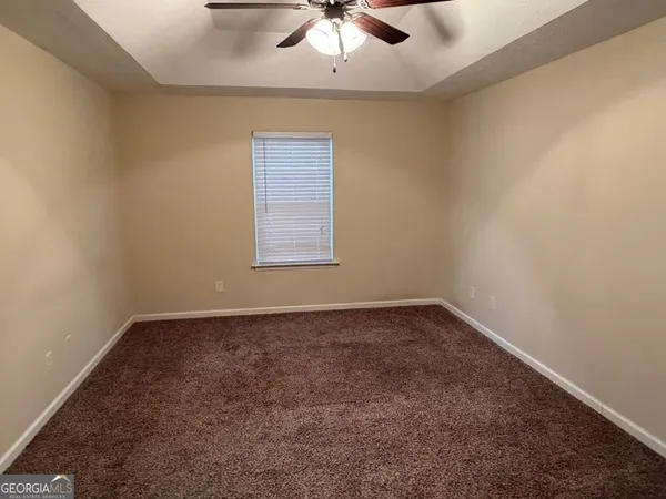 an empty room with a window and a fan