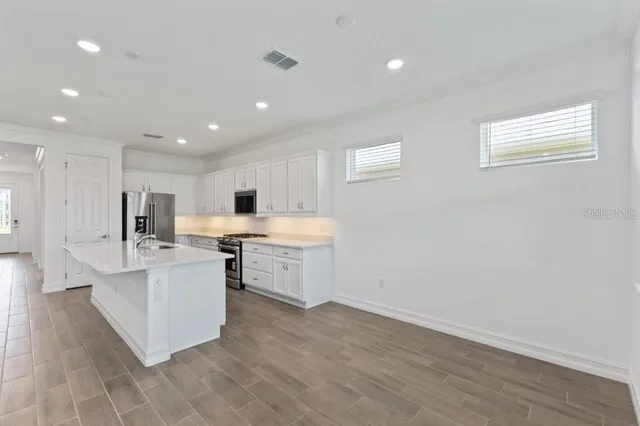 a large white kitchen with a stove a sink dishwasher and a refrigerator with wooden floor