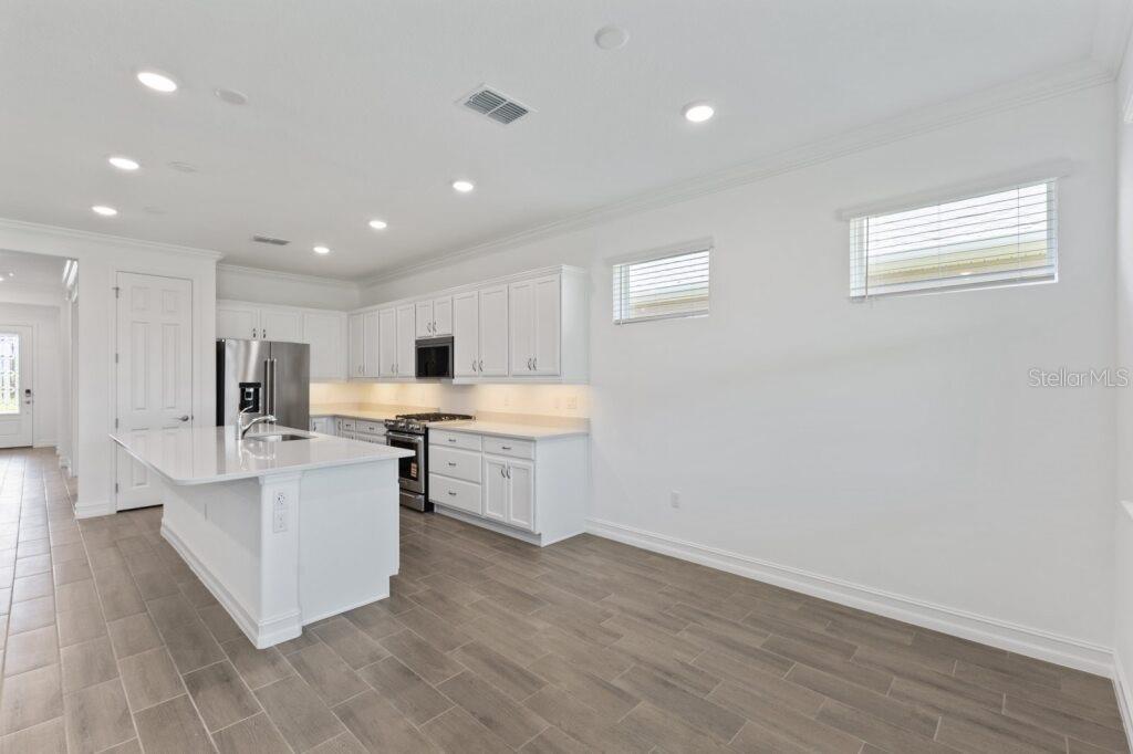 3223 Northwest 52nd Avenue Road Ocala, FL 34482 - Photo 13 of 25 a large white kitchen with a stove a sink dishwasher and a refrigerator with wooden floor