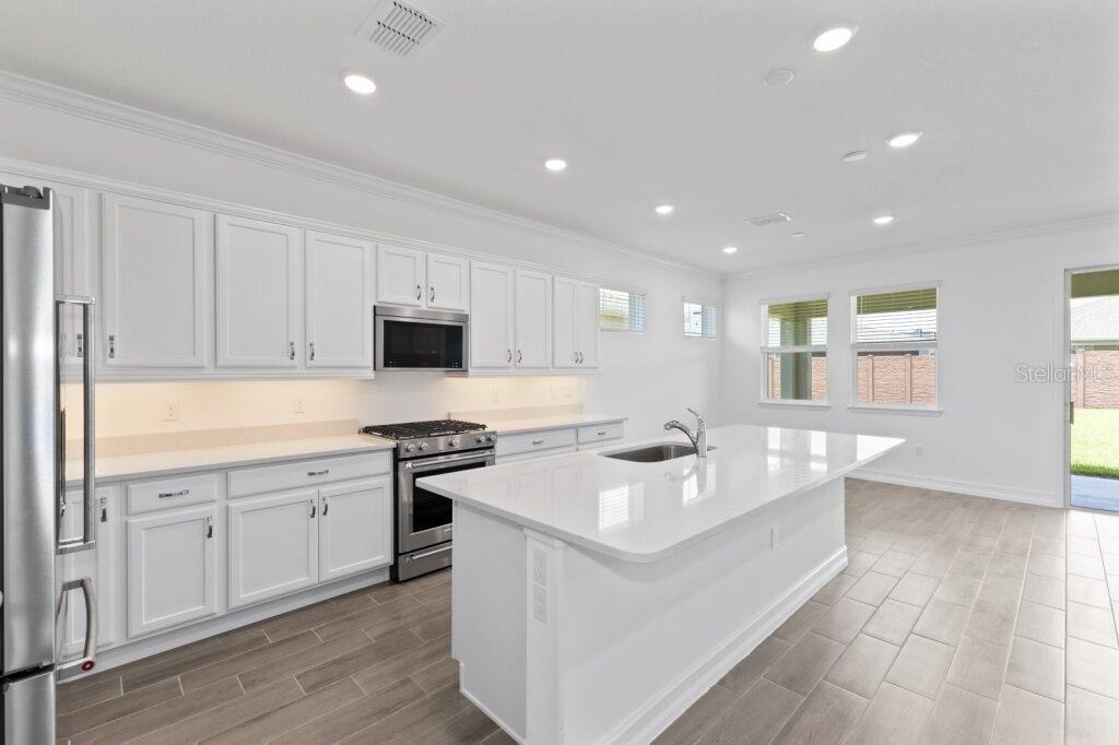 3223 Northwest 52nd Avenue Road Ocala, FL 34482 - Photo 4 of 25 a open kitchen with kitchen island a sink white cabinets and stainless steel appliances