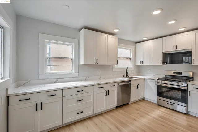 a kitchen with stainless steel appliances granite countertop a stove a sink and a microwave
