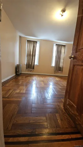 a view of an empty room with wooden floor and window