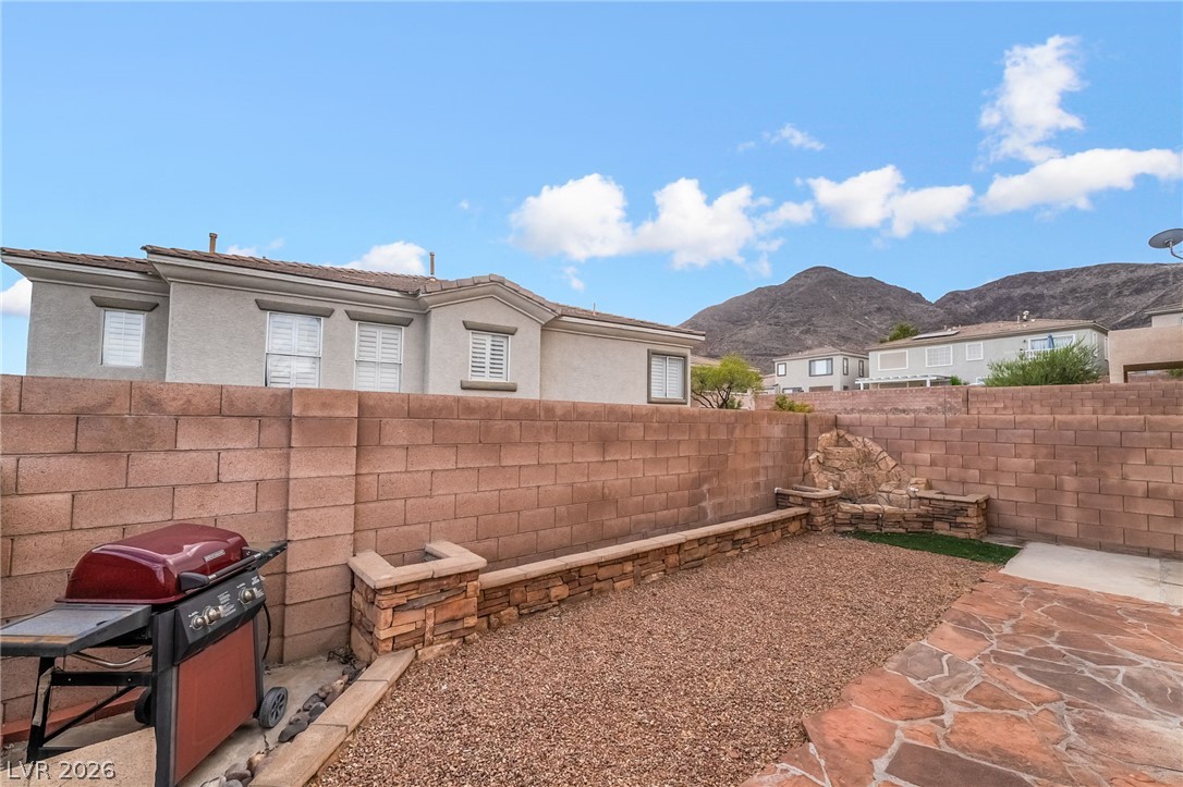224 Positive Point Street Henderson, NV 89012 - Photo 39 of 44 A stone-paved patio borders a fenced backyard featuring a built-in planter and gravel area.