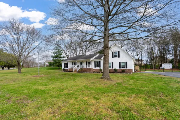 a house that is sitting in the grass with large trees