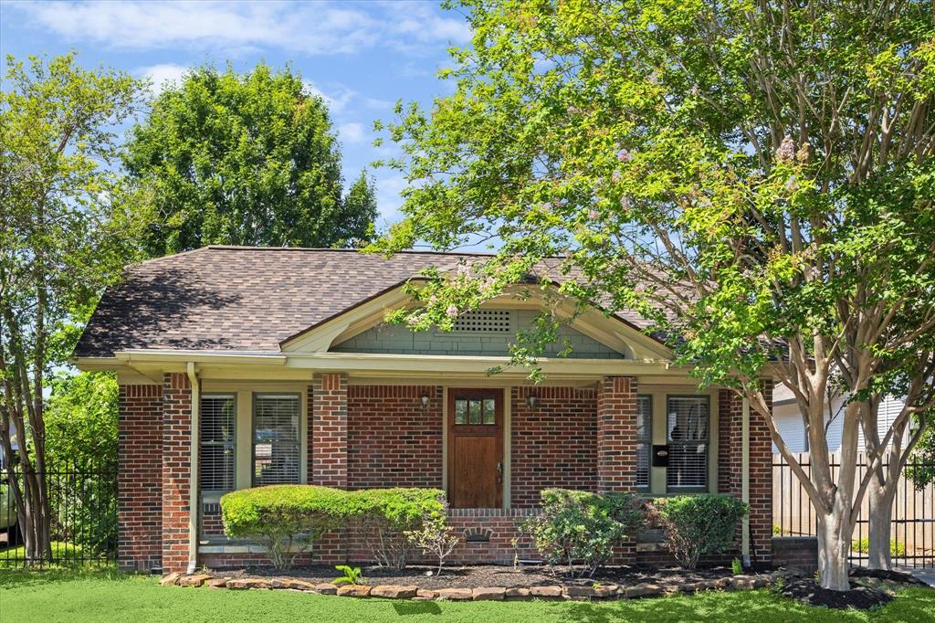 Quintessential Norhill Brick Bungalow, featuring lush trees, deep driveway, automatic gate, 2 car garage plus workshop space, and a new roof.