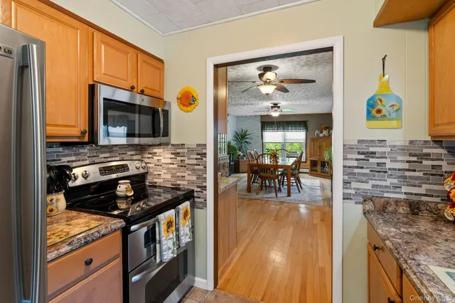 a kitchen with stainless steel appliances granite countertop a stove top oven a sink a dining table and chairs with wooden floor