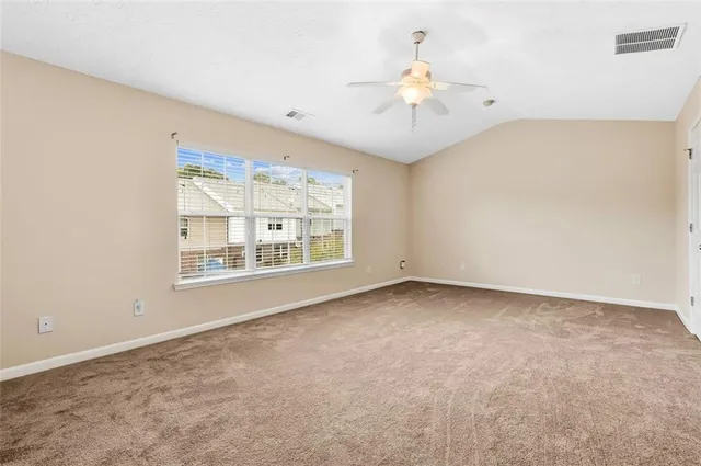 an empty room with a chandelier fan and windows