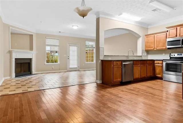 a view of an empty room with window and wooden floor