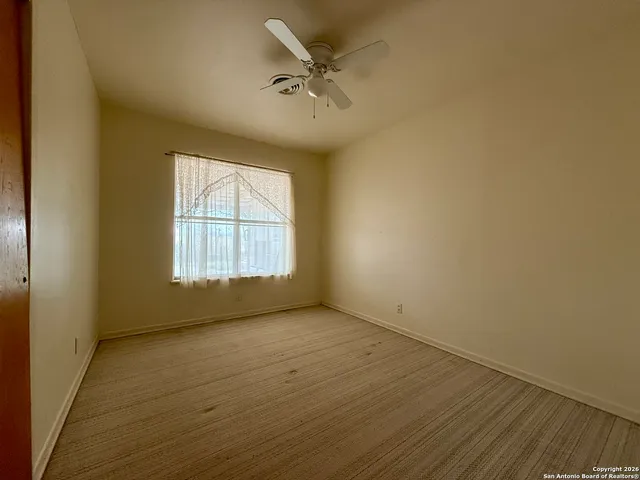an empty room with a window and a ceiling fan