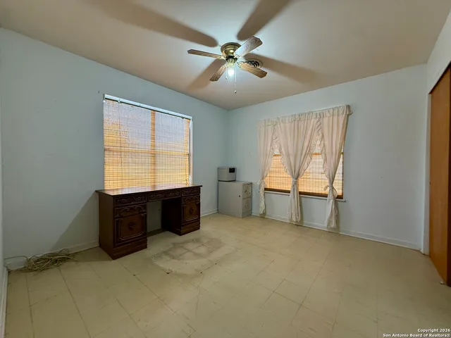 an empty room with windows and fan