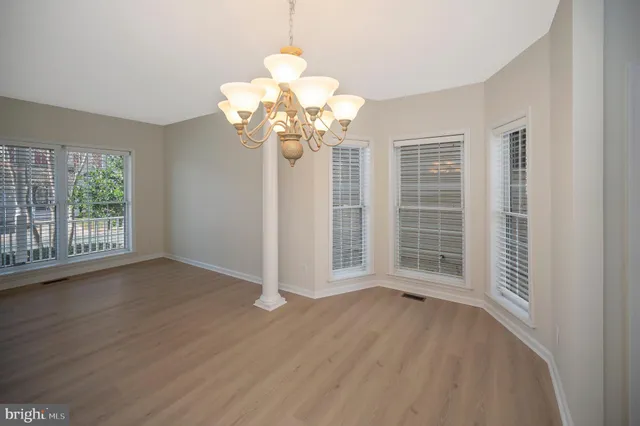 a view of a livingroom with a chandelier wooden floor and windows