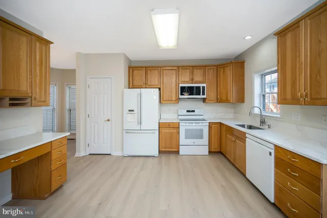 a kitchen with a refrigerator a stove top oven a sink dishwasher and wooden cabinets with wooden floor