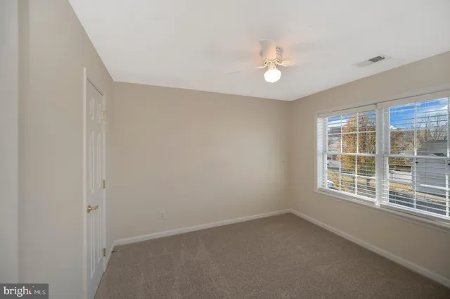 an empty room with a window and a fan