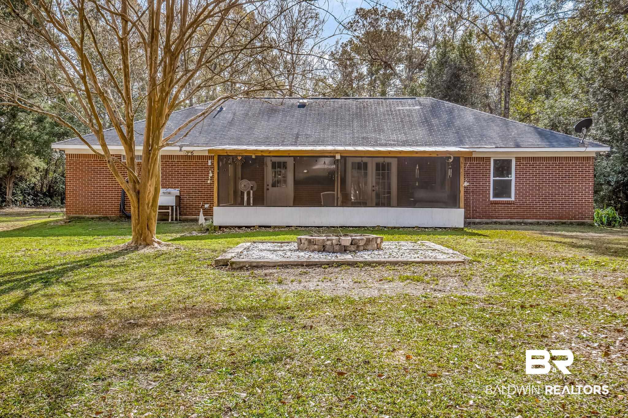 12199 Bay Road West Foley, AL 36535 - Photo 14 of 62 Back of house featuring a sunroom, a lawn, an outdoor fire pit, and brick siding