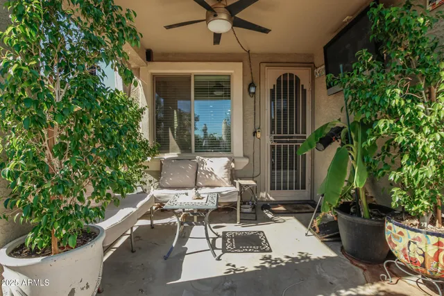 a view of a patio with table and chairs potted plants and floor to ceiling window