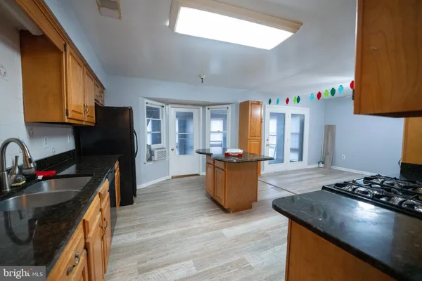 a kitchen with stainless steel appliances granite countertop a stove top oven a sink dishwasher and cabinets with wooden floor