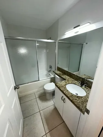 a bathroom with a granite countertop sink a toilet and a mirror